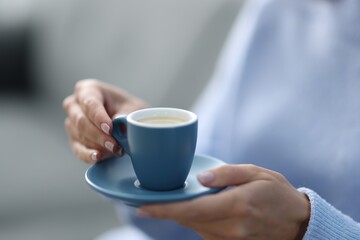 Woman having coffee break on blurred background, closeup