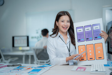 Young female UI UX designer presenting different wireframe layouts and screens for a new mobile application development project, working in a modern office