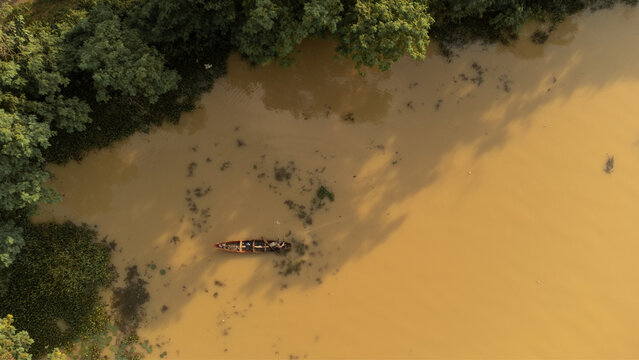Aerial view of a canoe gliding through the murky waters, cutting a path between the dark green vegetation, Alex Ekwueme Way, Abuja, Federal Capital Territory, Nigeria.