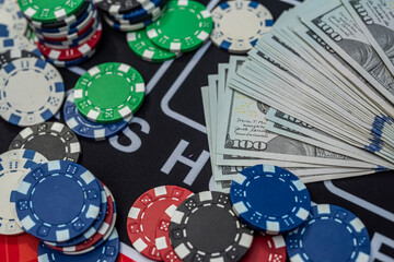 Colorful poker chips on stacks of US dollar bills symbolizing gambling, wealth, casino and betting concept
