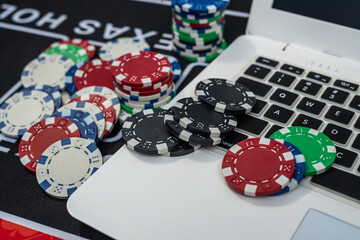 Colorful poker chips and laptop close up symbolizing online casino, gambling, betting and gaming concept