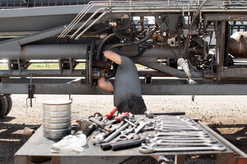 Hombre reparando maquinaria agr&iacute;cola con herramientas en primer plano