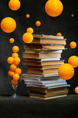 Still life with a stack of books and orange balloons