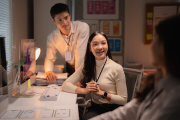 Diverse Asian business professionals are engaging in a meeting, discussing ideas, and working together on a project during a late night session in a modern office setup