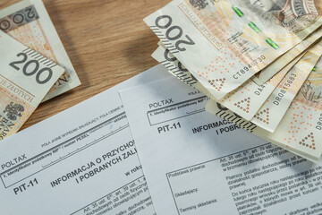 Obraz premium Polish PIT-11 tax form with 200 zloty banknotes, personal income tax and finance concept in Poland