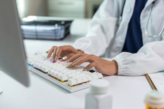 Doctor hands typing on a glowing computer keyboard, managing patient data and electronic health records in a medical office