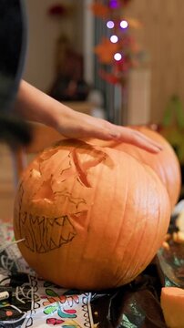 Close up of woman't hands carving a pumpkin for halloween