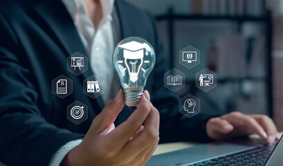 Businessman holding light bulb with graduation cap and education icons, symbolizing innovation, digital learning, knowledge development, online study, creative business ideas in modern technology.