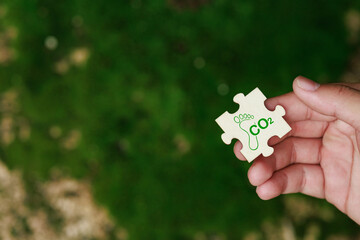 Hand holding a blue puzzle Carbon Footprint, Reducing CO2 Emissions and Promoting Sustainability, Reduce carbon and go green, carbon emission to net zero. Earth Day, and ESG.