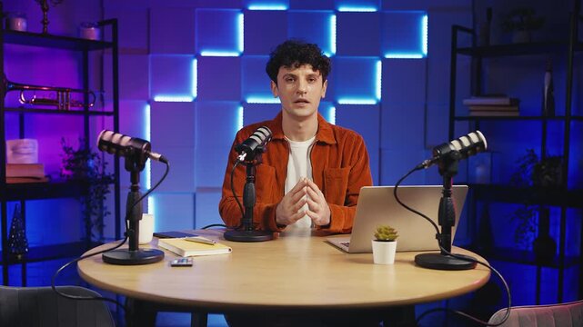 Male presenter recording podcast in studio, speaking confidently into microphone