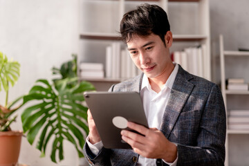 A man in a suit is looking at a tablet