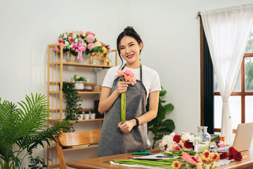 Adult Woman Florist Holding Flowers in Flower Shop or Studio Making Floral Arrangements Smiling with Flowers for Delivery on Table