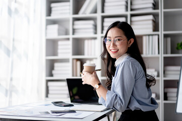 Accounting business concept, Accountant woman drinking coffee and writing information in notebook while