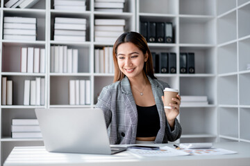 Accounting business concept, Accountant woman drinking coffee and typing data on laptop while working