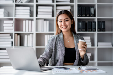Accounting business concept, Accountant woman drinking coffee and typing data on laptop while working