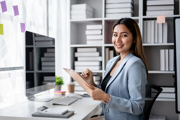 Accounting business concept, Accountant woman writing finance data on clipboard and working on computer