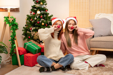 Two Young Women Celebrating Christmas with Red Noses Christmas Tree and Gifts Holiday Festive Season Joyful Smiling Decoration Xmas Celebration