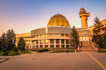 Scenic exterior view of the Almaty Pioneers Palace with its observatory tower and golden dome glowing in the evening sun in Almaty, Kazakhstan