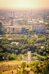 Scenic view of downtown Almaty, Kazakhstan, as seen from Kok Tobe Mountain at sunset, with the Koktobe roller coaster tracks visible in the foreground