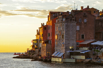 Coastal town buildings at sunset with people dining outdoors, Rovinj, Croatia