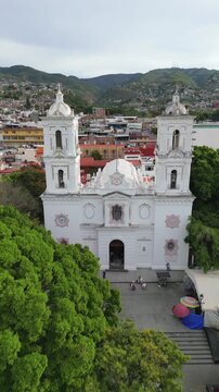Vertical aerial footage moving away from Chilpancingo Cathedral, uncovering full plaza and town view
