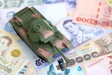 Thai baht currency money bills and toy tank close up. The concept of army funds and weapons sales
