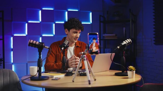 Male podcaster streaming live video on phone, commenting video game content
