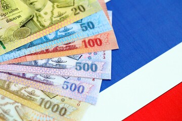 Obraz premium Thai baht currency money bills lies on flag close up. The concept of business and investment