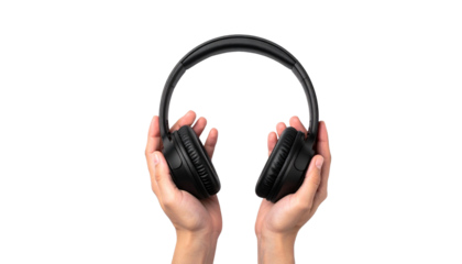 A person holding a pair of black headphones against a plain backdrop. The headphones are held out towards the viewer, emphasizing their features and design