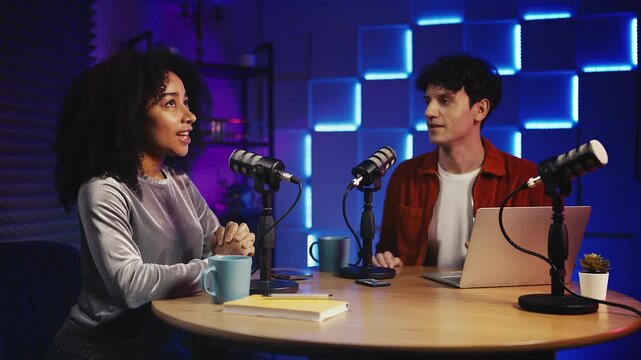 Two presenters recording podcast in studio, discussing hobbies and trends - Powered by Adobe