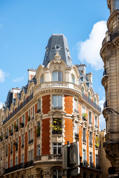View of the ornate architecture with red brick and beige stone, bathed in sunlight under a blue sky, architectural details, Paris, Ile-de-France, France.