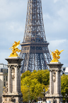 View of the Eiffel Tower rising gracefully behind the golden statues on the Pont Alexandre III bridge, bathed in sunlight, Paris, Ile-de-France, France.