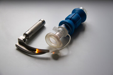 A laryngoscope and a breathing bag for newborns are on a white table. Horizontal shot.