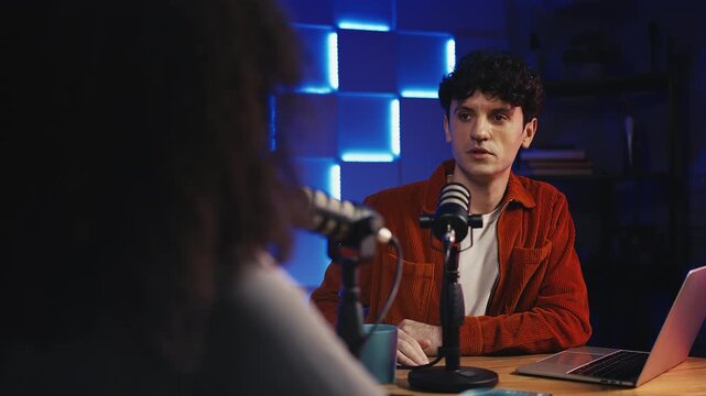 Male radio anchor interviewing female guest in studio, recording podcast