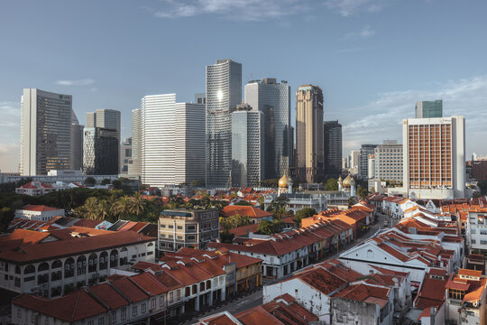 View of a blend of old and new architecture, where vibrant orange rooftops meet the sleek, towering skyscrapers under a clear sky, Singapore, Singapore.
