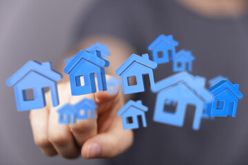 Hand pointing towards 3D blue house icons, symbolizing property, real estate, and home ownership....