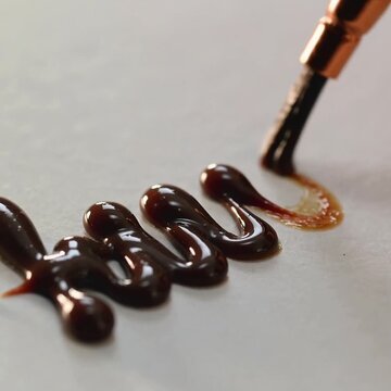 Video de un texto escrito con un pincel de tinta de chocolate, escritura continua, pintar, dibujar sobre papel o fondo claro, en diagonal, apetitoso