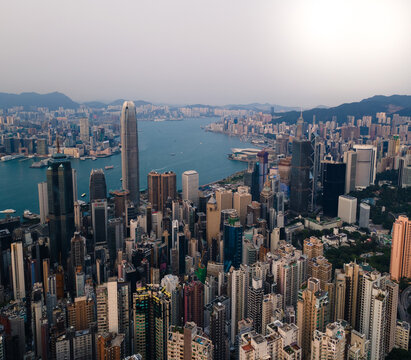 View of towering skyscrapers piercing the sky, a vibrant cityscape reflecting in the harbor's waters, capturing the energy of urban life, Hong Kong, Hong Kong Island, Hong Kong.