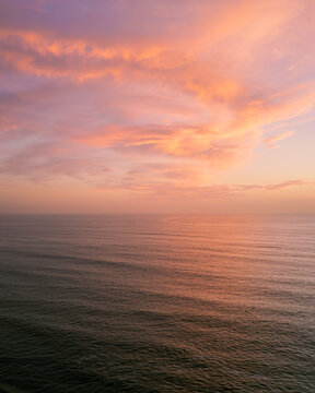 Aerial view of a tranquil ocean reflecting the soft pastel hues of the dawn sky, a serene moment captured from above, Los Angeles, California, United States.