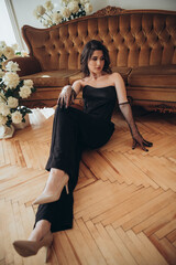 Stylish woman in black dress sitting with bare feet