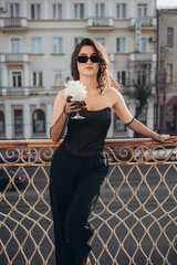 Confident woman in sunglasses holding coffee cup outdoors