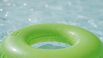Front view of a green rubber ring for swimming pool floating in water
