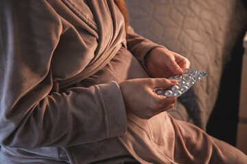 Pregnant young woman taking pills or vitamins
