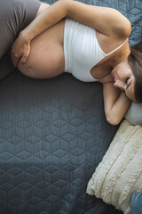 Pregnant young woman lies in the bed