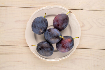 Sweet plums on a wooden table, close-up, top view.