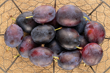 Sweet plums on jute cloth, close-up, top view.