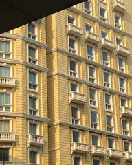 Obraz premium Yellow building facade with balconies and windows under a concrete structure