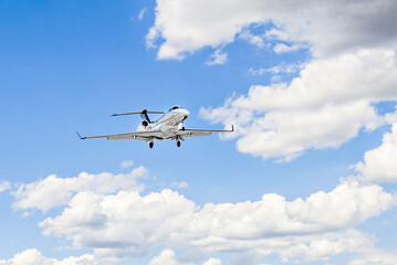 Private business plane flying under blue sky with white clouds	