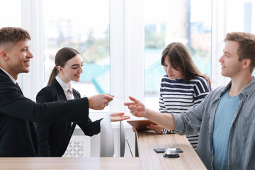 Receptionist and hostess working with guests at reception desk in hotel