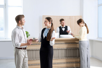 Receptionist giving passport to guest in hotel, selective focus